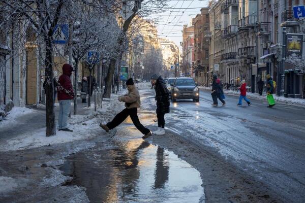 People cross a flooded and ice-covered section of the street after a waterpipe burst during sub-zero temperatures in Kyiv.
