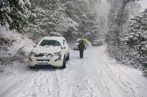 A commuter walks down a road during snowfall, at Joshimath in Chamoli district, Uttarakhand.