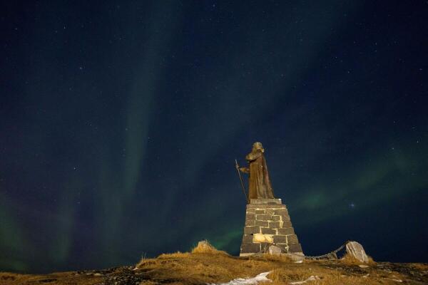 The Aurora Borealis, also known as the "northern lights", illuminates the sky over the statue of Hans Egede in Nuuk, Greenland.