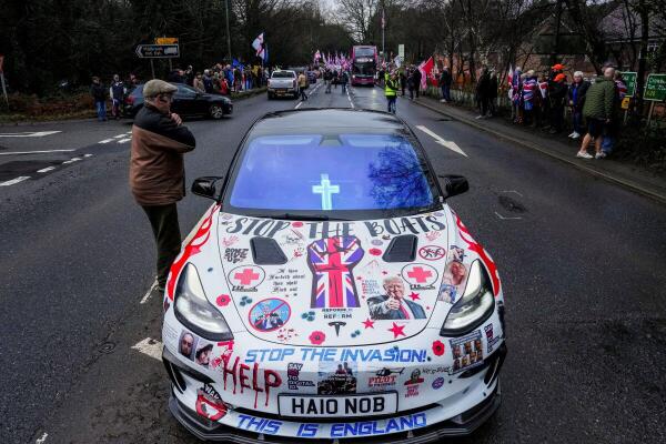 A person stands next to a car covered with slogans during a protest against the use of a former army barracks to house asylum seekers in Crowborough, East Sussex, Britain.