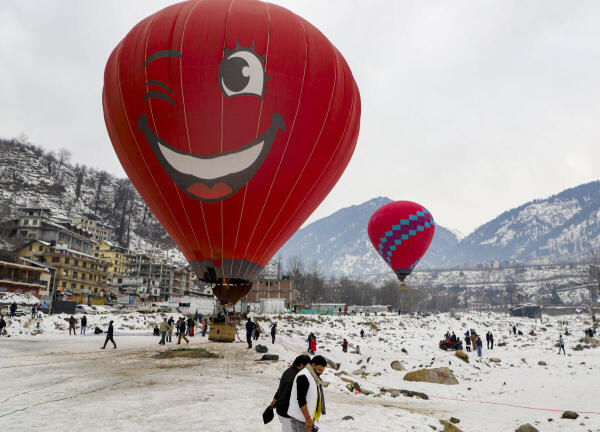 People take a hot air balloon ride at a snow-covered valley near the Beas river, in Manali.
