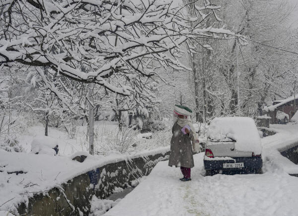 A woman walks on a snow-covered stretch amid heavy snowfall, in Srinagar.