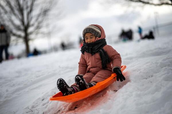 A girl slides down a snow-covered hill, as a major winter storm spreads across a large swath of the United States, as it is seen from North Bergen.