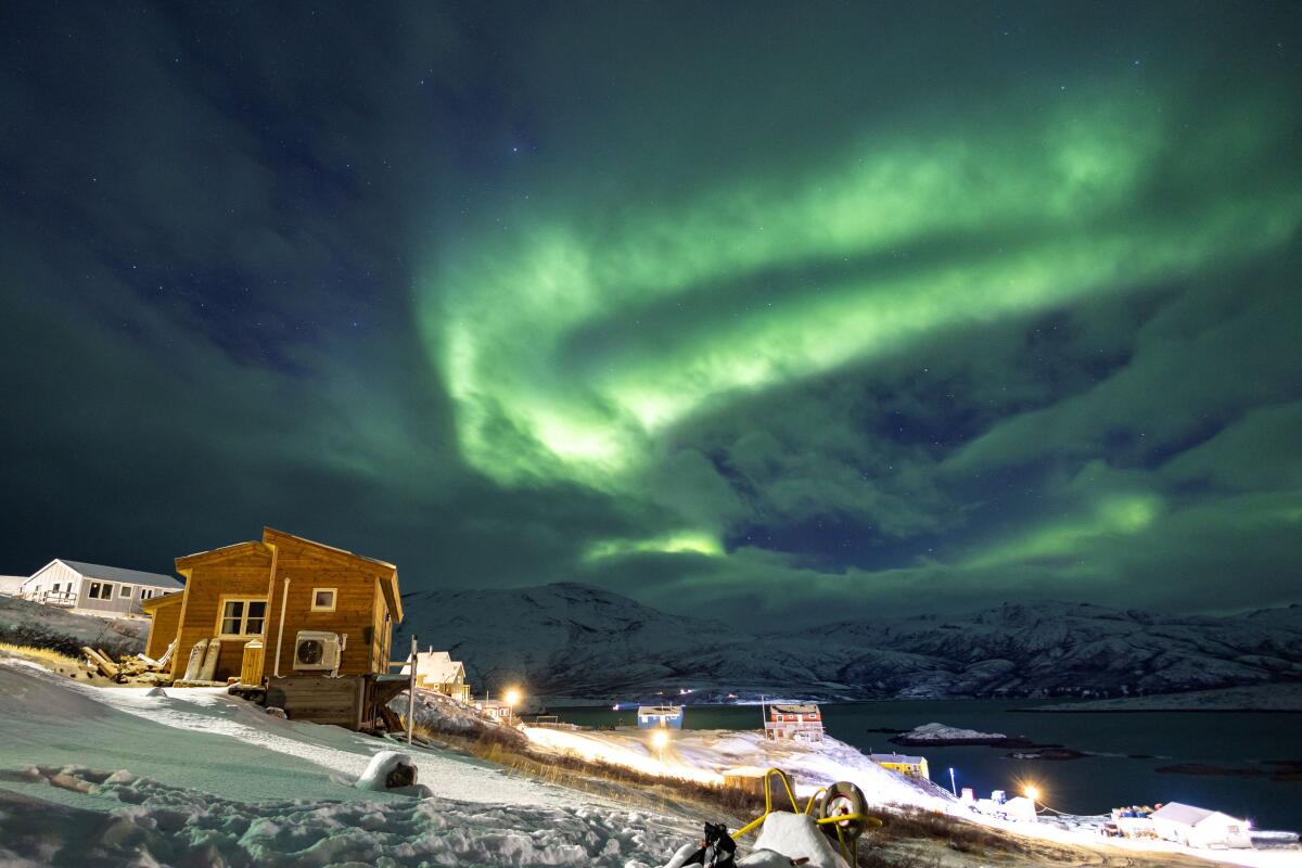 The Aurora Borealis, also known as the "northern lights", illuminates the sky over houses in Kapisillit, Greenland, January 20, 2026. The concept that ownership is shared collectively is central to the Inuit identity. It has survived 300 years of colonisation and is written into law: People can own houses, but not the land beneath them.