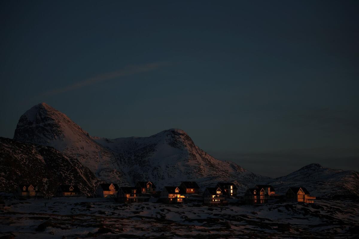 The setting sun reflects off the windows of houses in Nuuk, Greenland.