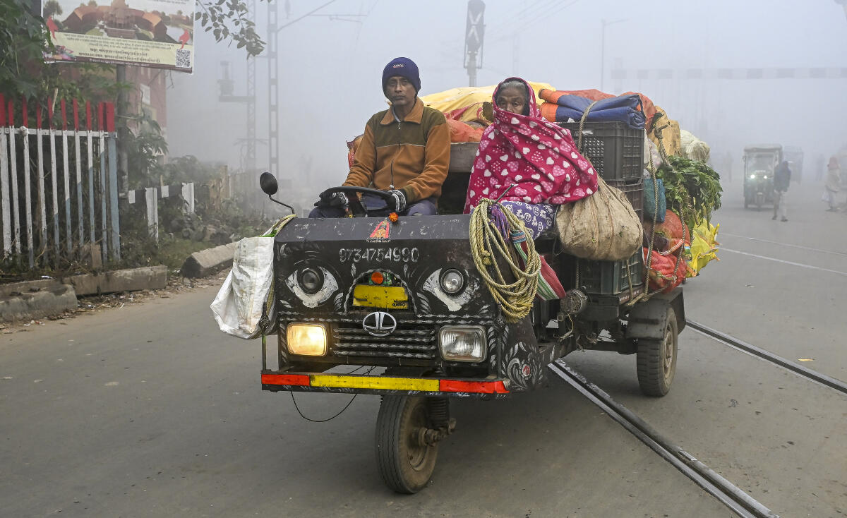A vendor crosses railway tracks on a foggy winter morning, in Nadia, West Bengal, Friday, Feb. 6, 2026.