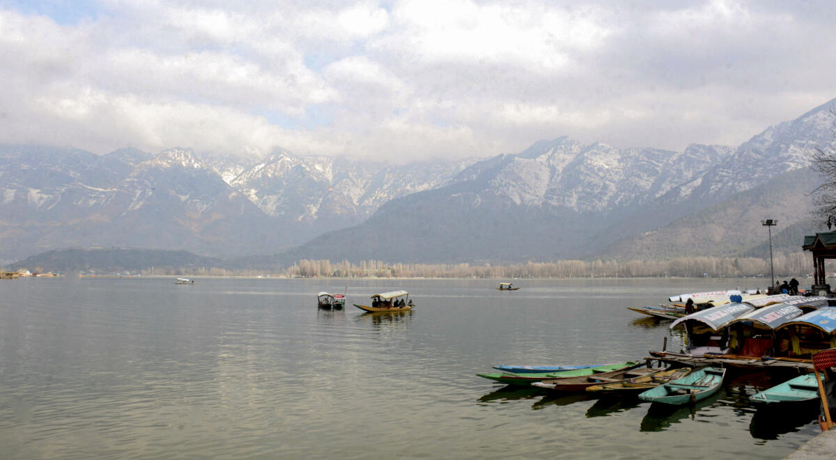 People take a 'shikara' ride on Dal lake under the snow-covered Zabarwan mountains after the city received snowfall, in Srinagar, Sunday, Feb. 8, 2026.