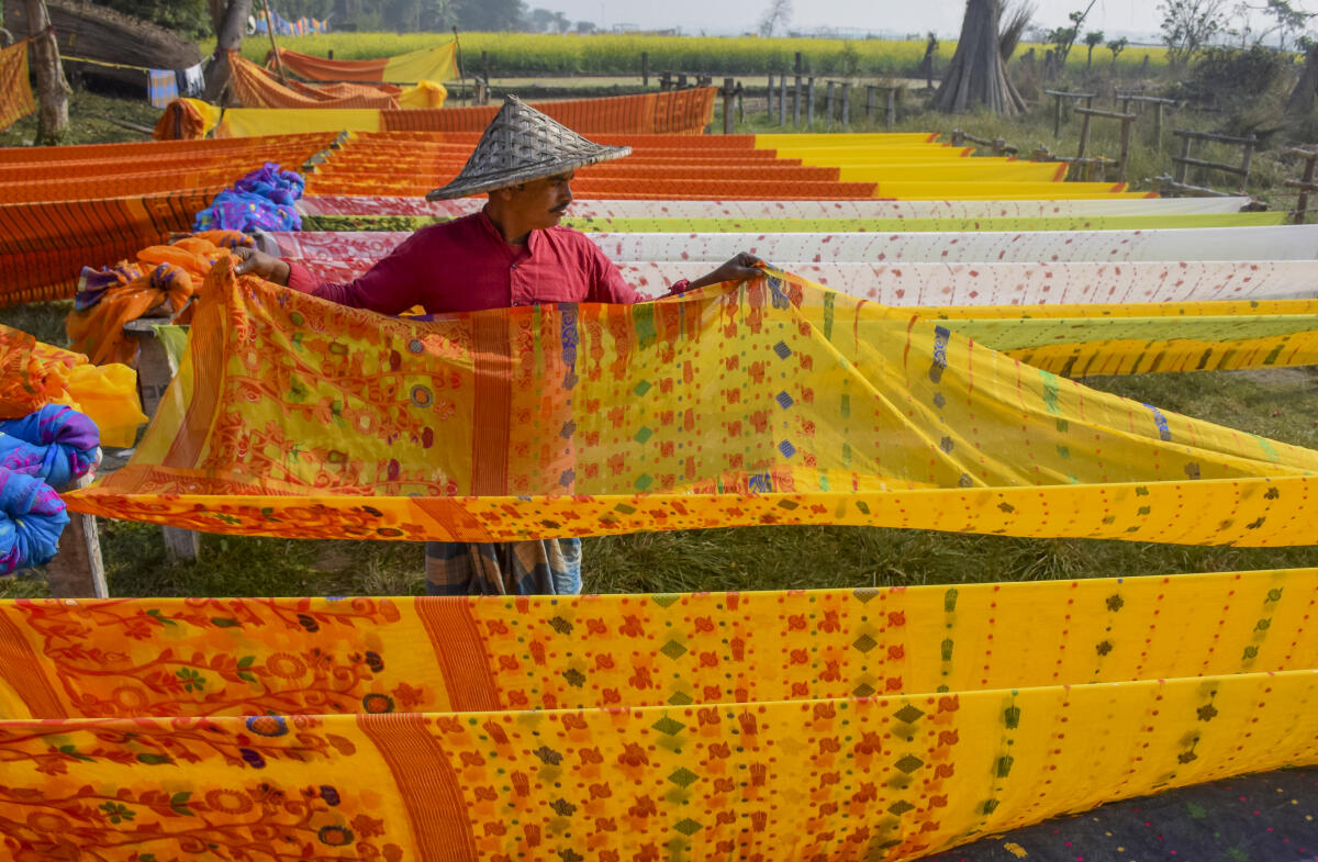 A worker dries freshly dyed sarees at a handloom unit, in Nadia district, West Bengal, Monday, Feb. 9, 2026.