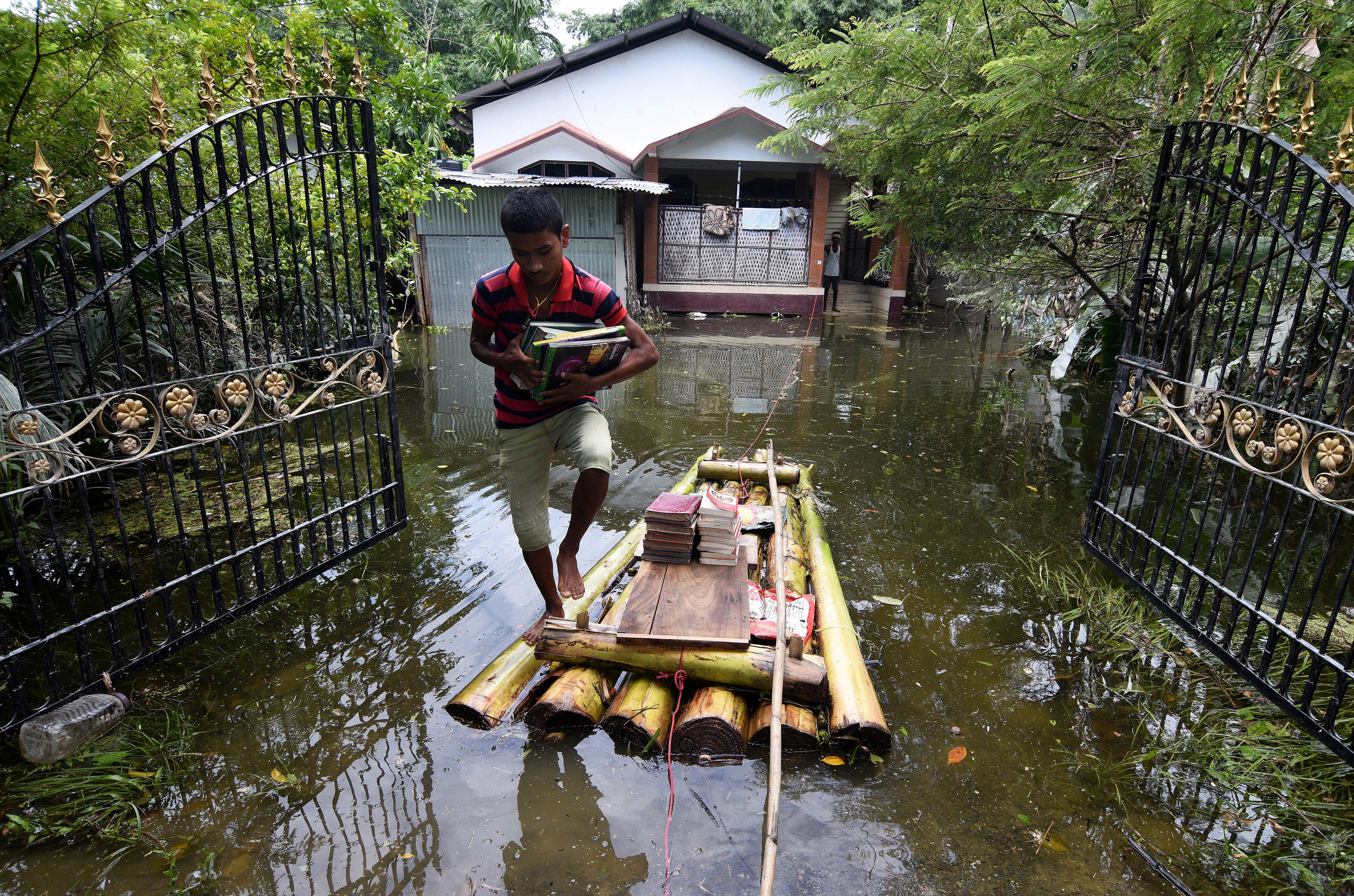 A boy uses a banana raft to transport his books in Jakhalabandha area in Nagaon district