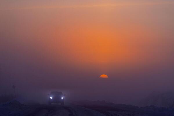 A vehicle travels along a road at sunrise during an extreme cold weather warning, in Yellowknife, Northwest Territories, Canada.