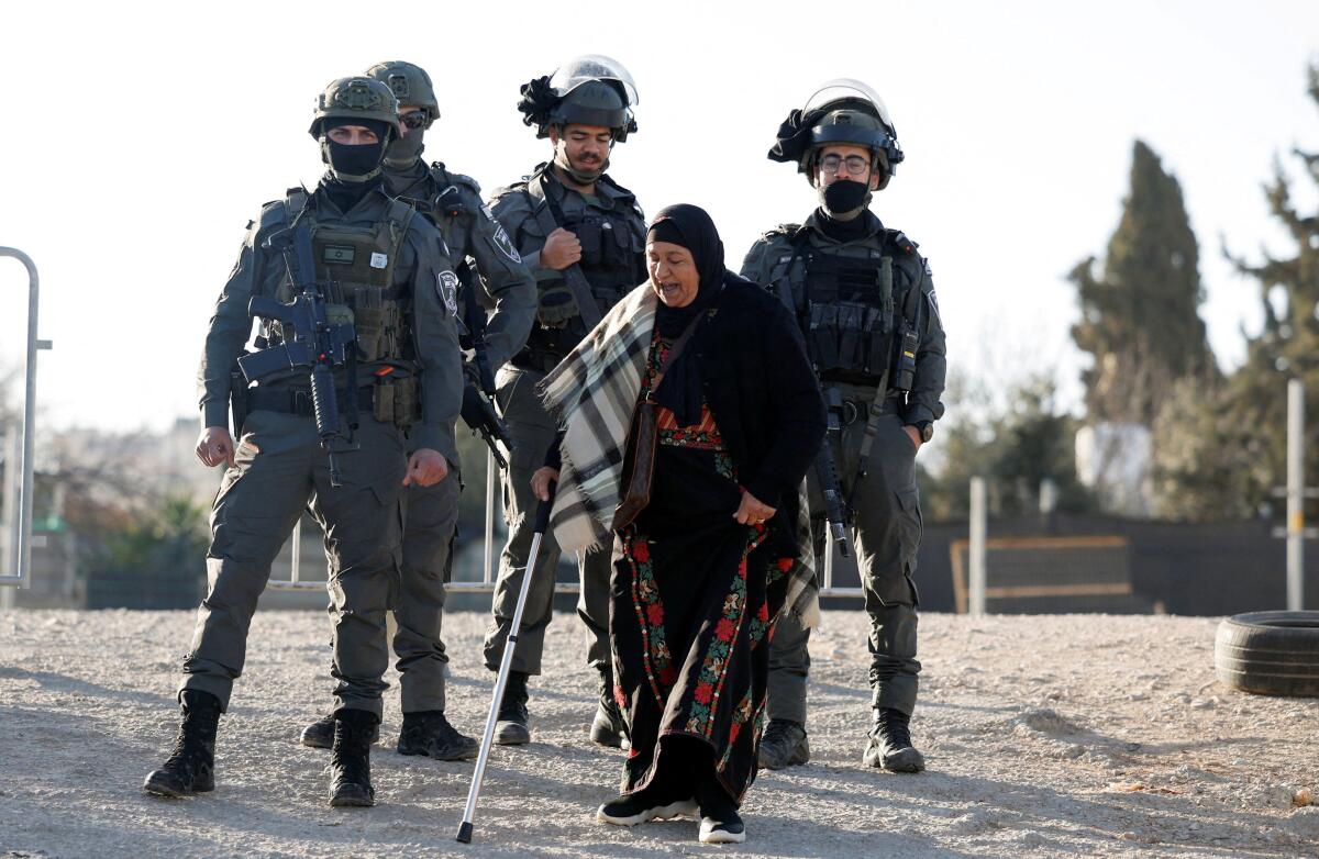 A Palestinian woman, who was denied entry to Jerusalem, walks next to members of Israeli troop, as people make their way to Al-Aqsa compound, also known to Jews as the Temple Mount, in Jerusalem's Old City, to attend the first Friday prayers during the Muslim holy fasting month of Ramadan, near the Qalandia checkpoint in the Israeli-occupied West Bank.