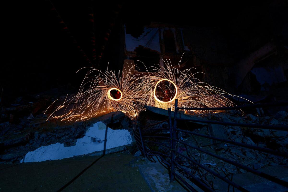 Palestinians spin steel wool sparklers during the holy month of Ramadan, amidst the rubble of residential buildings destroyed during the two-year Israeli offensive, in Gaza City.