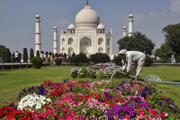 A worker waters the garden where flowers bloom, at the Taj Mahal, in Agra, Uttar Pradesh.