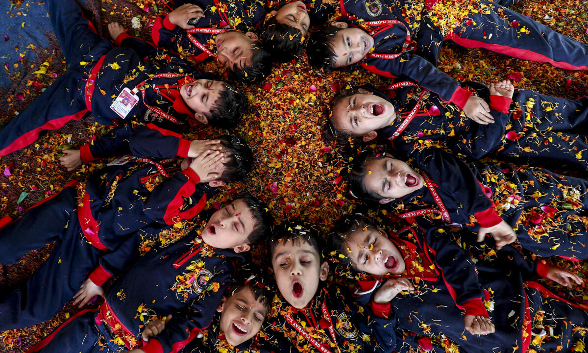 School children play Holi with flowers at a school, in Jammu
