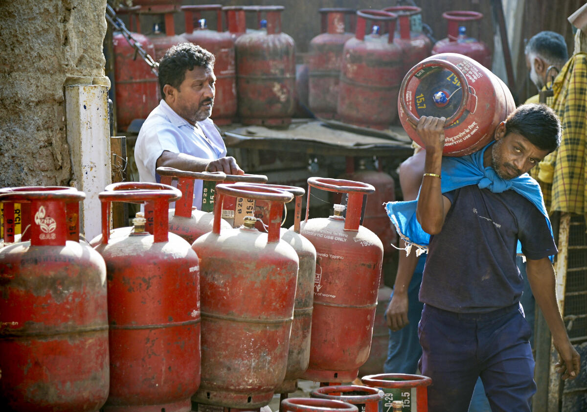 Workers load LPG cylinders at a depot following recent price hikes for both domestic and commercial units, in Nagpur.