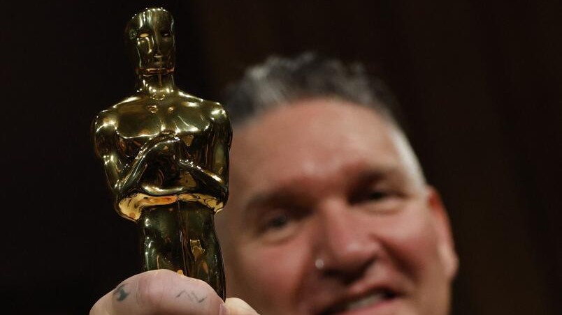 Jordan Samuel poses with the Oscar for Best Makeup and Hairstyling for Frankenstein.