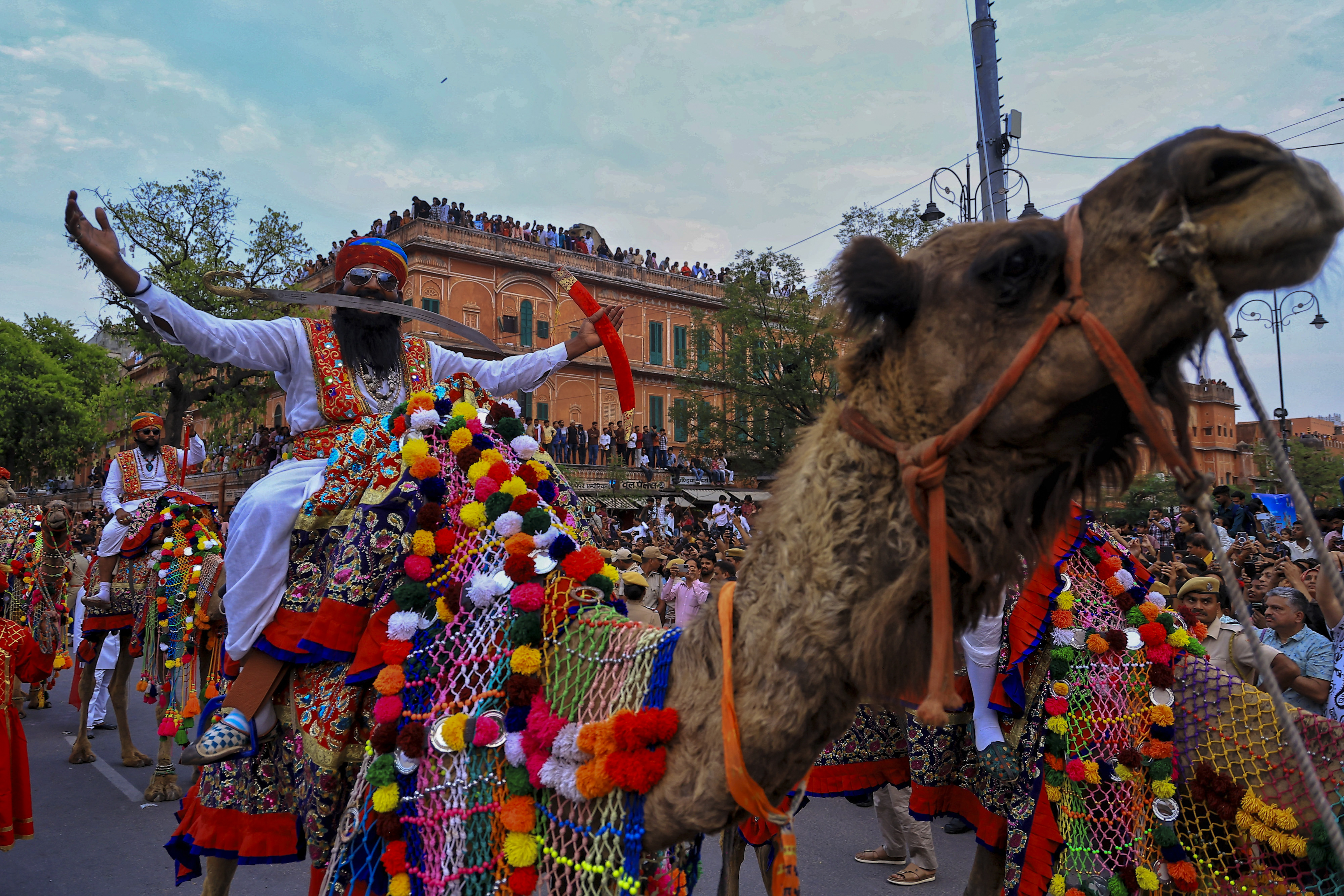 An artist holds a sword in his mouth while moving on a decorated camel during the ‘Gangaur’ festival, at Tripolia Bazar in Jaipur.