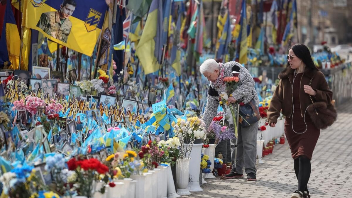 A woman visits a makeshift memorial with the names of fallen service members written on Ukrainian and other national flags in Kiev.