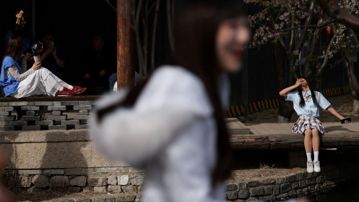 Women pose for pictures near blossoming flowers at a park in Beijing, China.