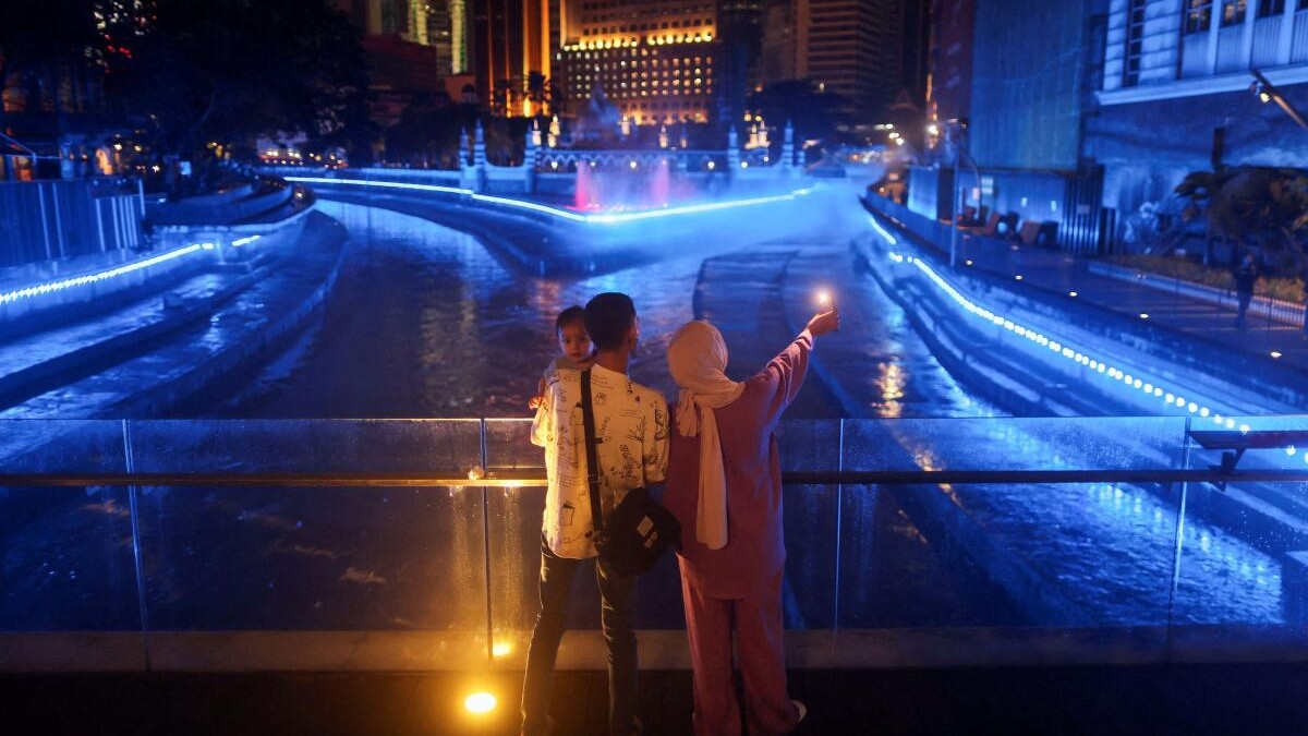 A family takes a selfie as they stand at the River of Life in Kuala Lumpur, Malaysia.