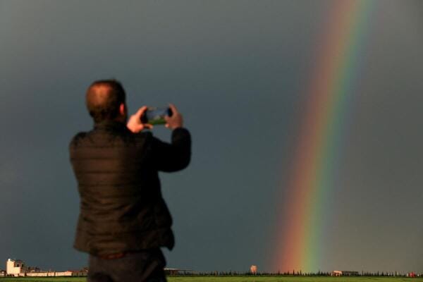 A man records images of a rainbow after heavy rain in Qamishli, Syria.
