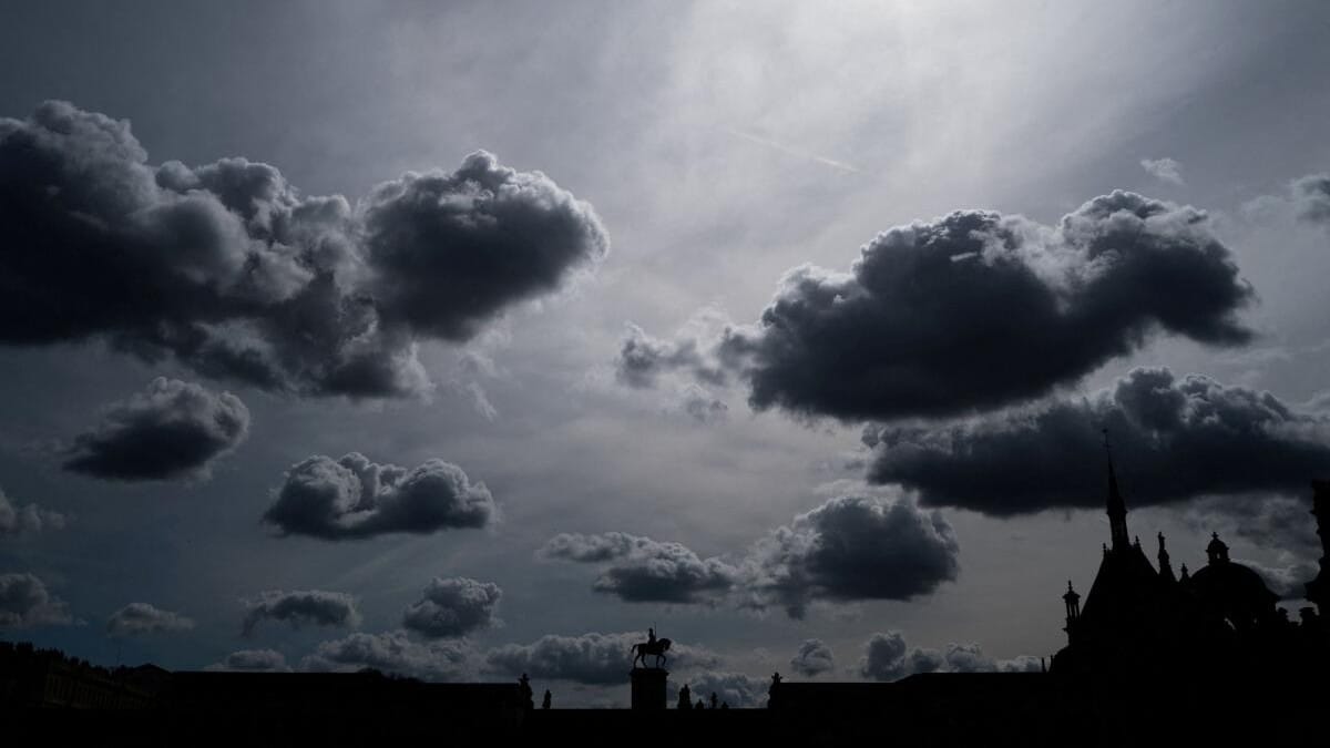 Tourists walk near the equestrian statue of Anne de Montmorency on a cloudy day at the Chateau de Chantilly, near Paris.