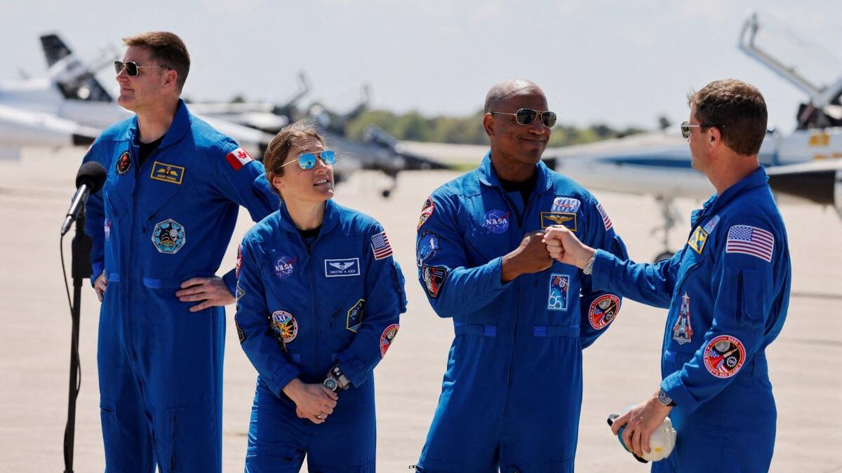 NASA astronauts Reid Wiseman and Victor Glover greet each other next to NASA astronaut Christina Koch and CSA (Canadian Space Agency) astronaut Jeremy Hansen, at Kennedy Space Centre.