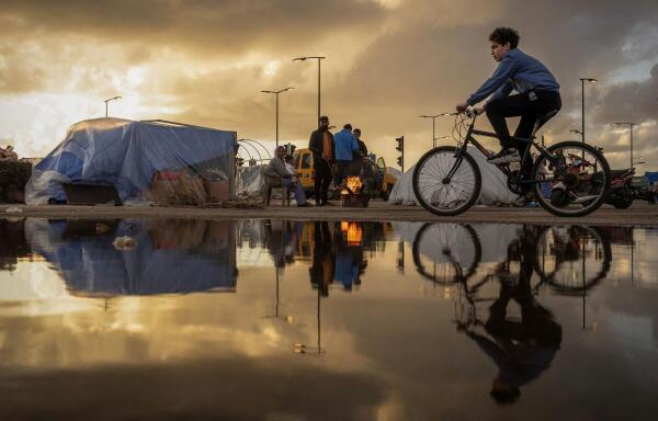 A family stand next to a fire outside their tent, at a temporary encampment for displaced people, amid escalating hostilities between Israel and Hezbollah, as the US-Israel conflict with Iran continues, in Beirut, Lebanon.