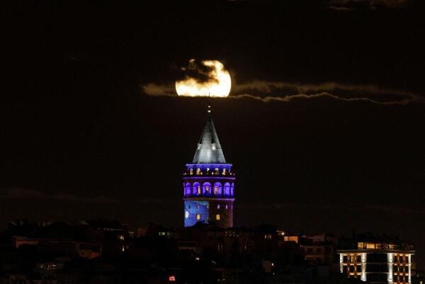 A full moon rises over the Galata Tower in Istanbul, Turkey.