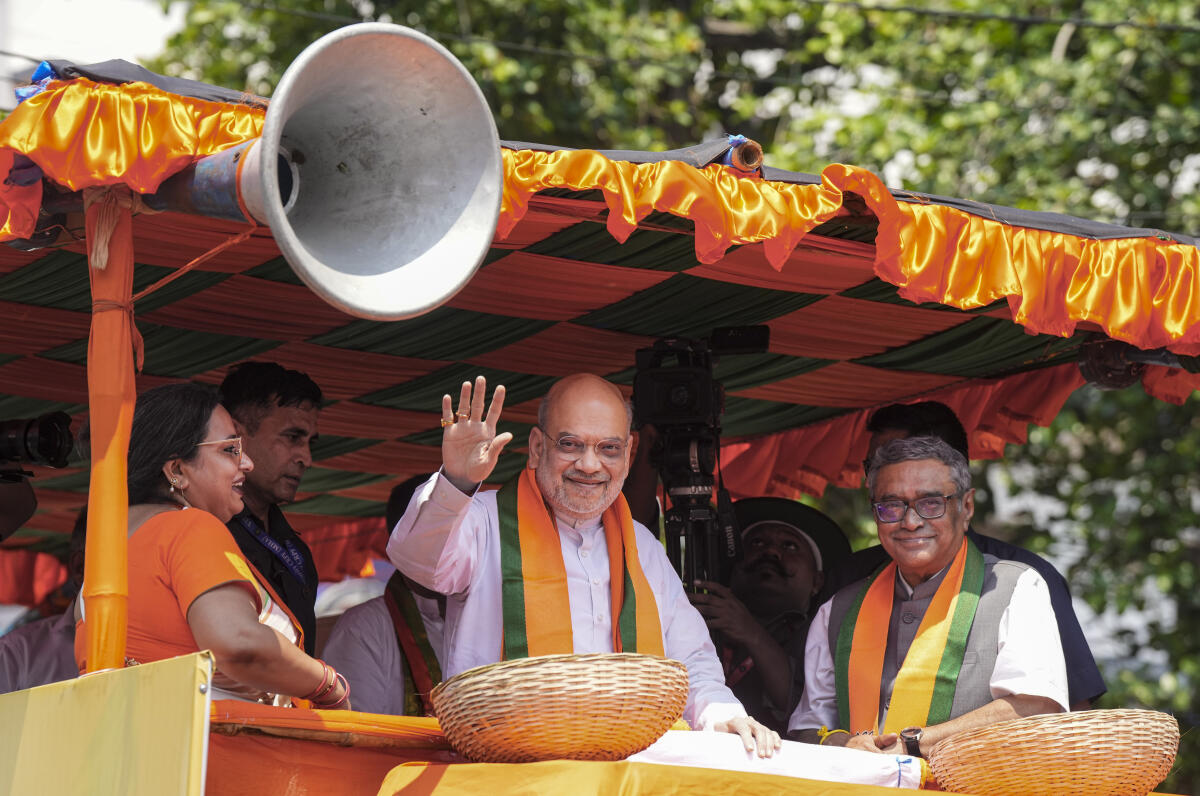 Union Home Minister Amit Shah, centre, during a roadshow for filing of nomination papers by BJP candidates Swapan Dasgupta, right, from Rashbehari, Shatorupa, left, from Ballygunge Assembly constituencies, in Kolkata, West Bengal. PTI