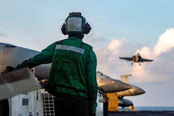 A US Sailor observes flight operations as an F/A-18E Super Hornet, attached to Strike Fighter Squadron 14, prepares to make an arrested landing on the flight deck of Nimitz-class aircraft carrier USS Abraham Lincoln supporting Operation Epic Fury during the Iran war at an undisclosed location.