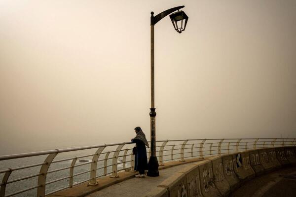 A woman looks at the sea as dust covers the city, amid escalating hostilities between Israel and Hezbollah, as the U.S.-Israel conflict with Iran continues, in Beirut, Lebanon.