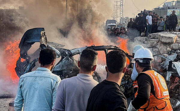 Palestinians inspect the site of what medics said was an Israeli airstrike on a car near the entrance to Zawayda town, amid the US-Israeli conflict with Iran, in the central Gaza Strip.