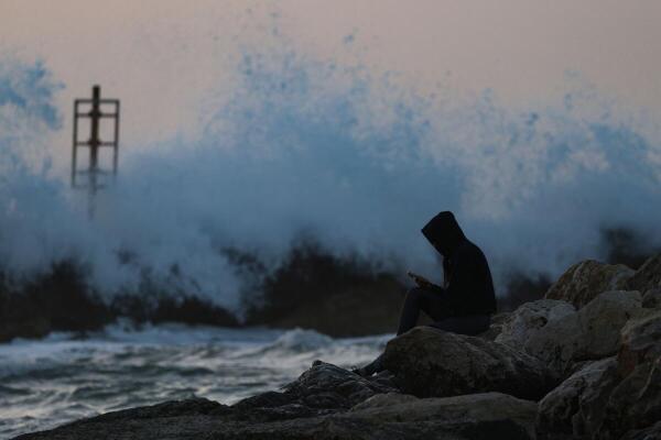 A woman uses her cell phone by the sea, amid the US-Israel conflict with Iran, in Tel Aviv, Israel.