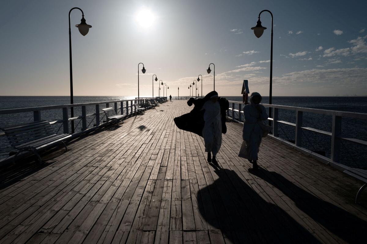 Nuns walk along Orlowo pier on a sunny spring morning in Gdynia, Poland.
