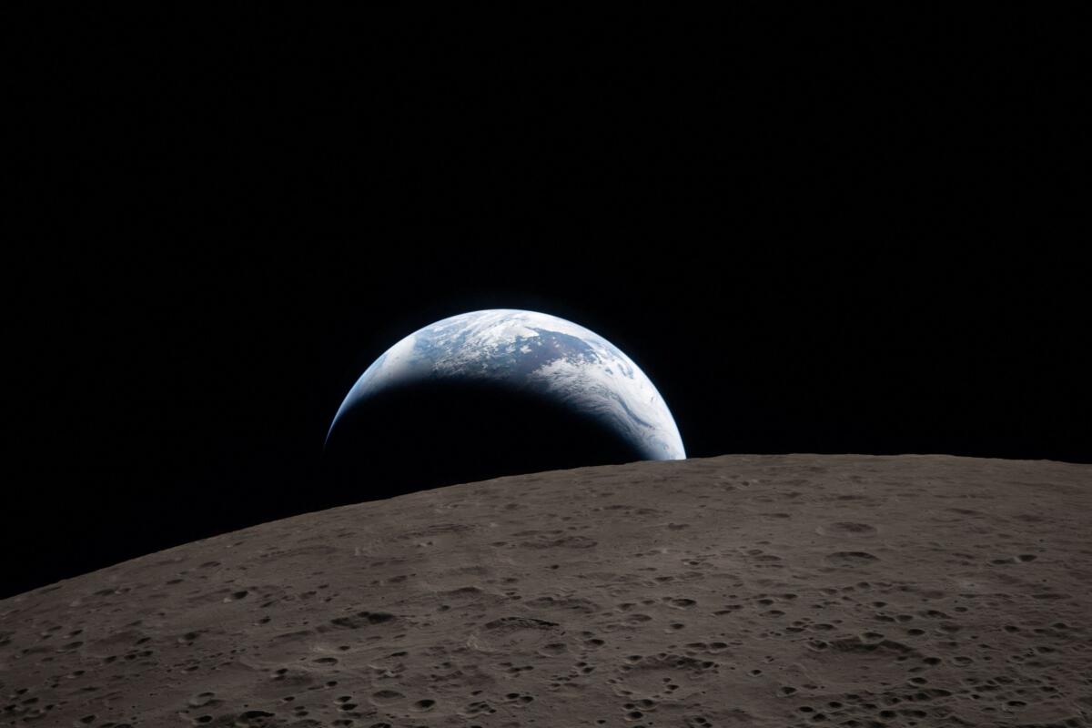 A view of Earth, partially hidden behind the Moon, captured through the Orion spacecraft window.