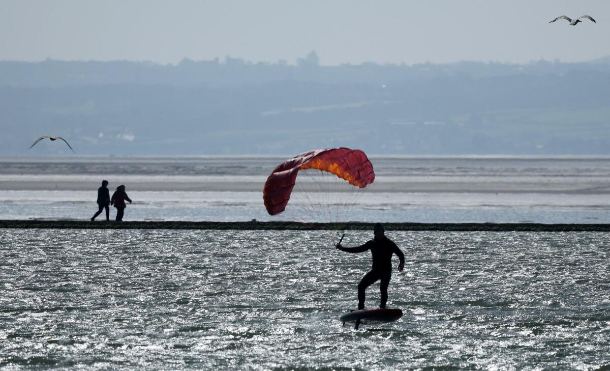 A man rides a kite foil across the marine lake at West Kirby, Britain.