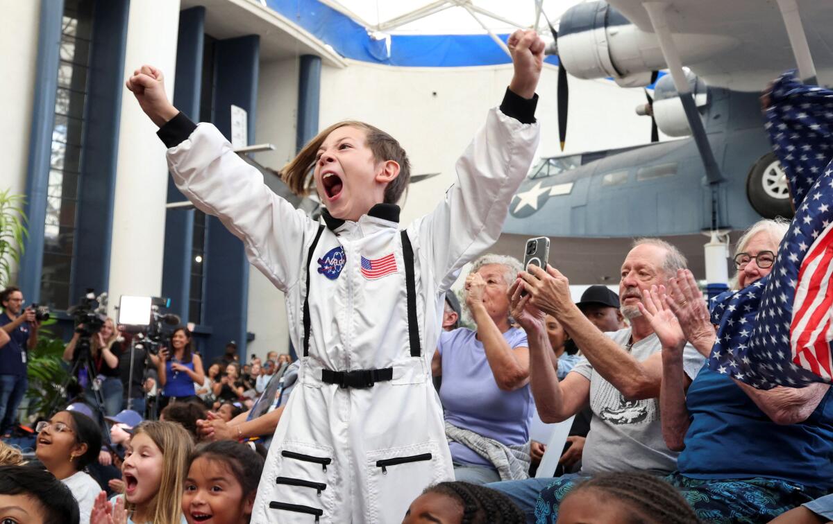 Crowds watch the Artemis II Orion capsule splash down off the coast of San Diego at the Air and Space Museum in San Diego, California.