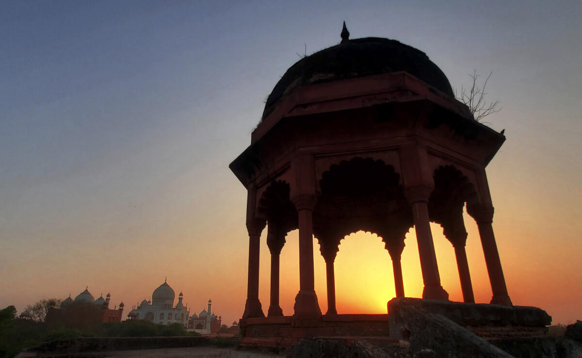  The sun sets behind a 'chhatri', umbrella-shaped pavilion, near the Taj Mahal, in Agra