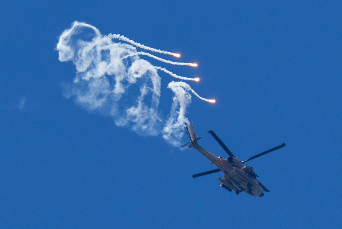 Israeli Apache helicopter releases flares as it flies over Lebanon as seen from Israel