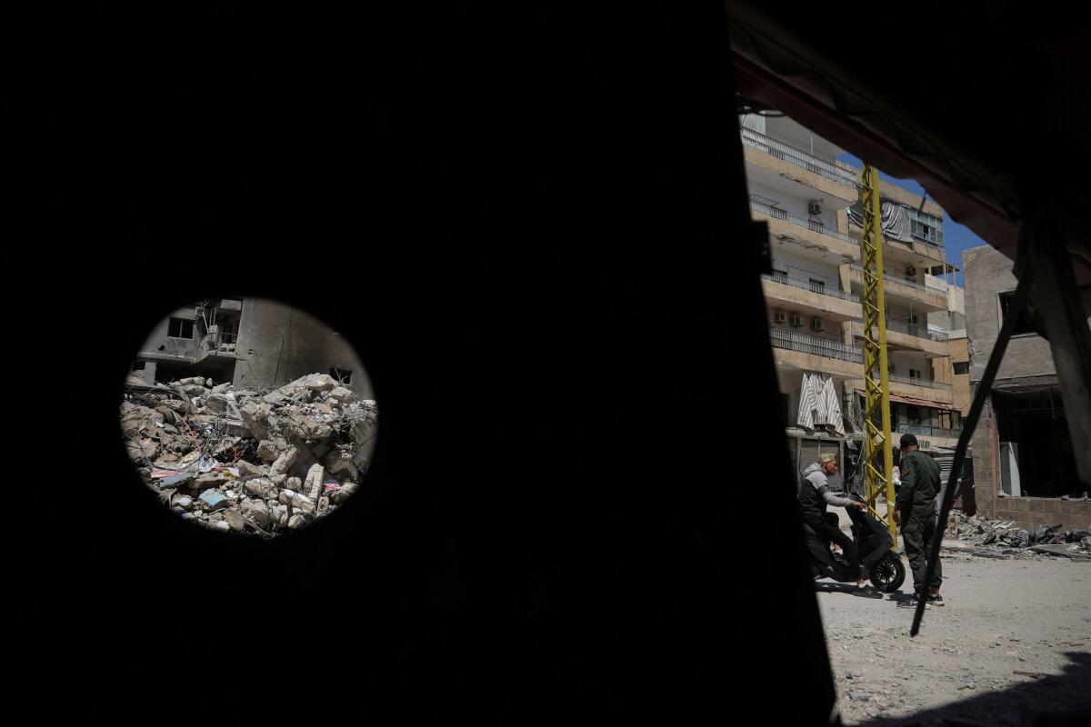 A municipality police officer talks with a person in an area damaged during Israeli strikes