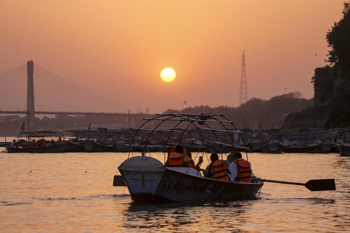 Visitors take a boat ride in the Yamuna river during sunset, in Prayagraj