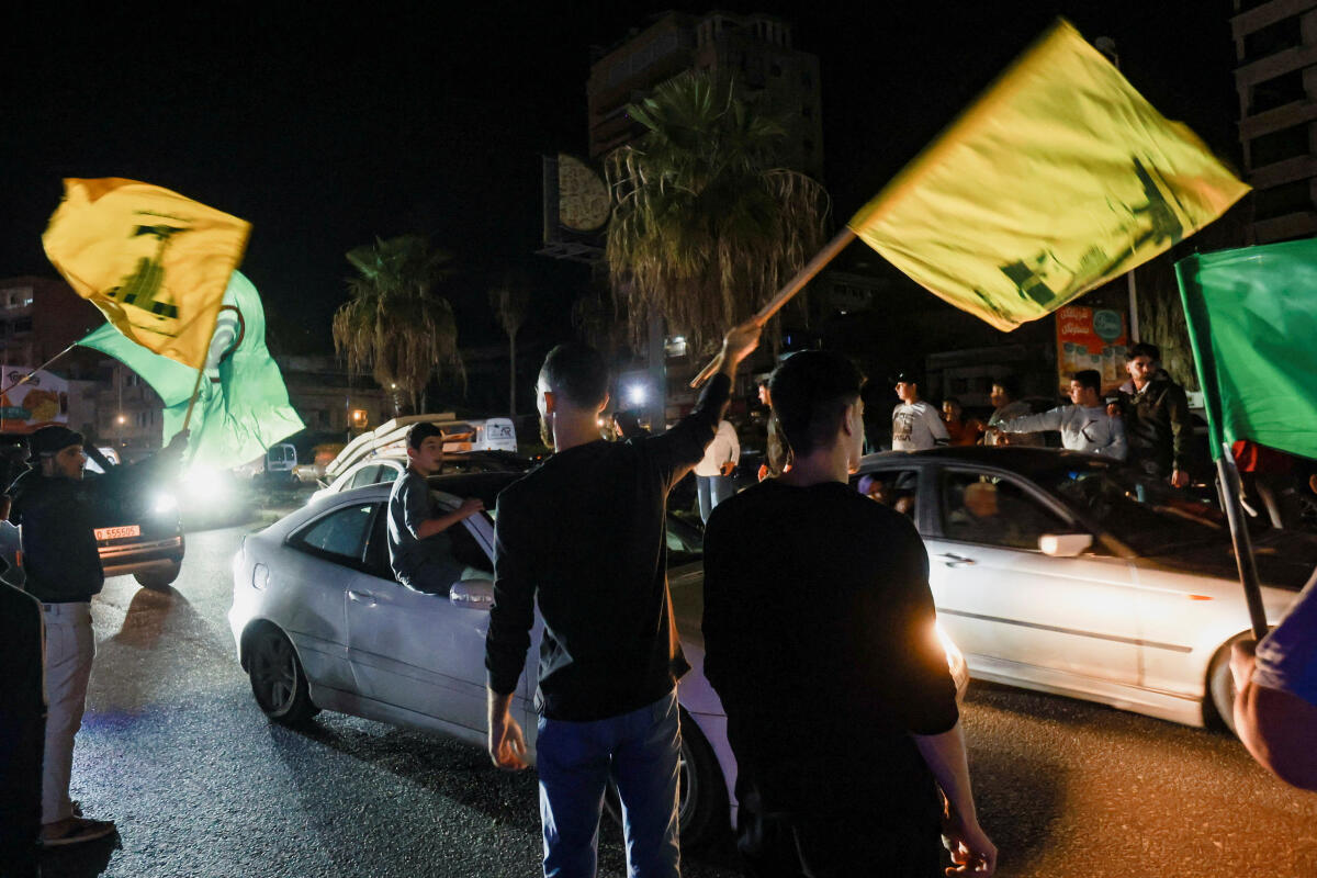 Men wave flags as displaced people return to their homes after a 10-day ceasefire between Lebanon and Israel went into effect, in Sidon, Lebanon. Reuters