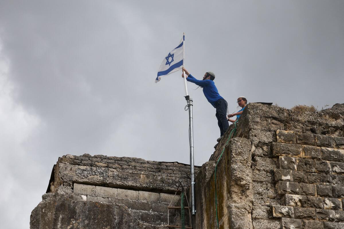 Israeli settlers place an Israeli flag atop a building, on the day of the re-establishment of the settlement of Sa-Nur, which was evacuated as part of Israel’s 2005 disengagement, in Sa-Nur in the Israeli-occupied West Bank.