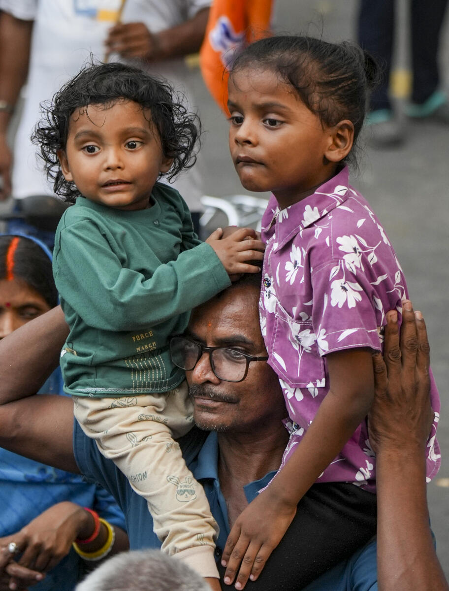 A man carries children on his shoulders as he waits before Prime Minister Narendra Modi's roadshow in Kolkata.
