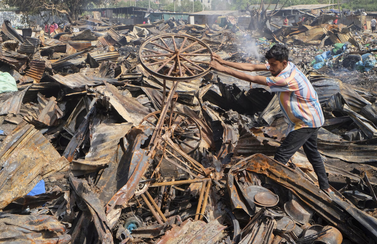A man sifts through charred remains at an area after a fire broke out at a plastic factory and warehouse and spread to nearby units, at Bajghera area, in Gurugram.
