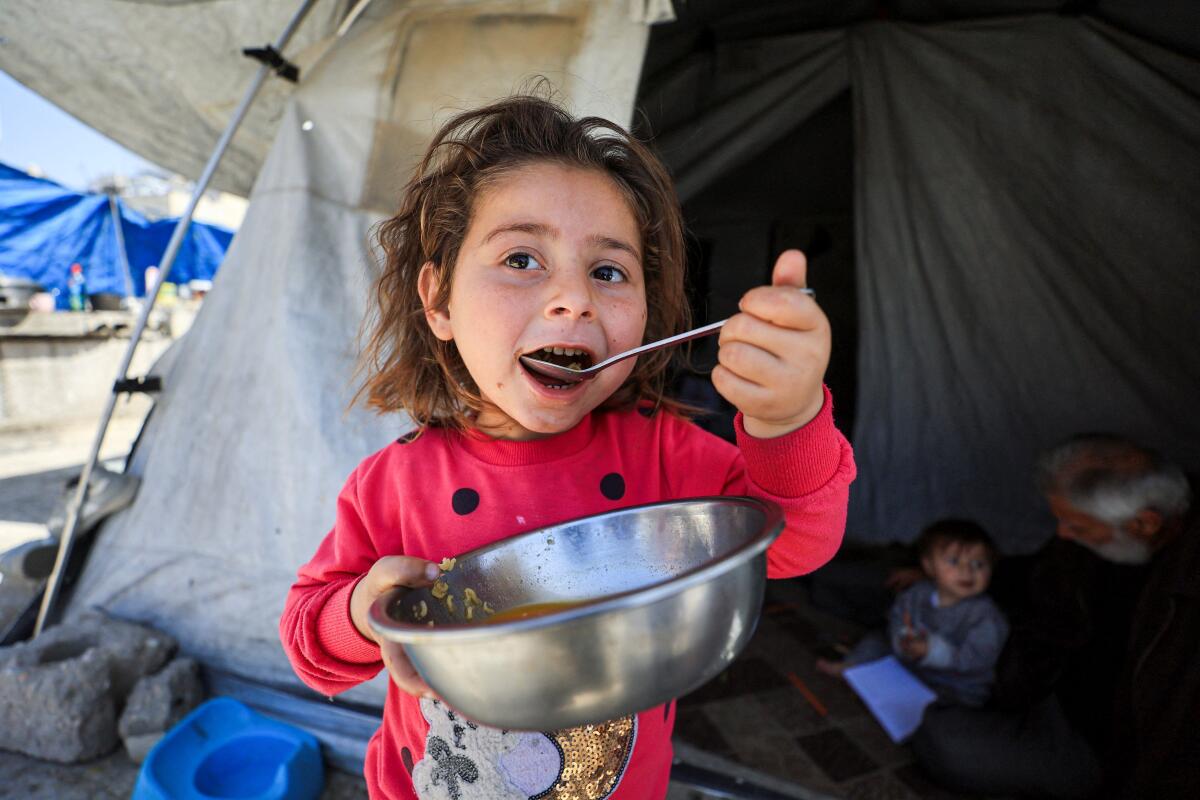 A displaced Palestinian girl eats outside a tent at a camp sheltering displaced people in Gaza City, April 28, 2026.