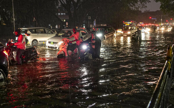Commuters pull their two-wheelers through a waterlogged road amid a traffic jam after heavy rainfall, in Bengaluru, Karnataka.