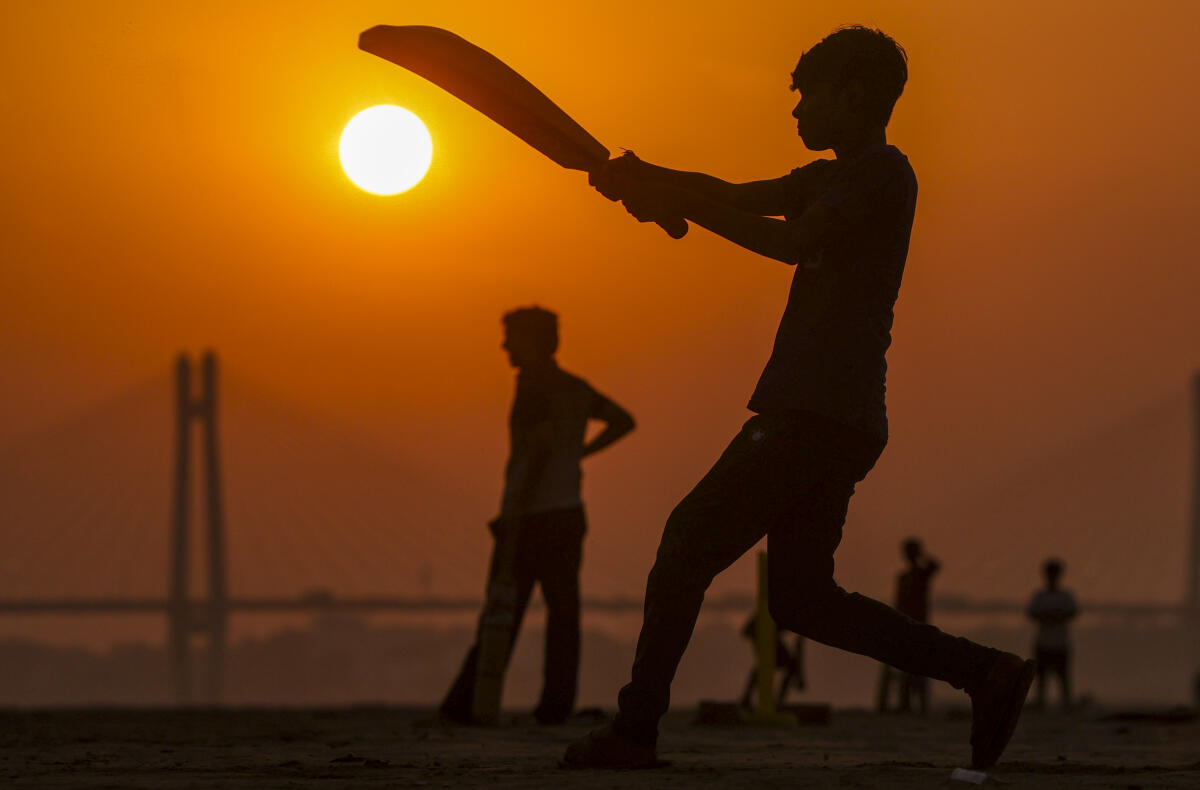 A young man playing cricket is silhouetted against the setting sun on the banks of the Ganga river, in Prayagraj, Uttar Pradesh, Thursday, April 30, 2026.