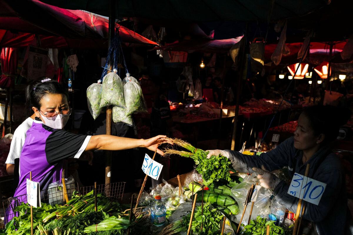 A woman buys a vegetable at a stall at a fresh market in Bangkok, Thailand, April 30, 2026. 